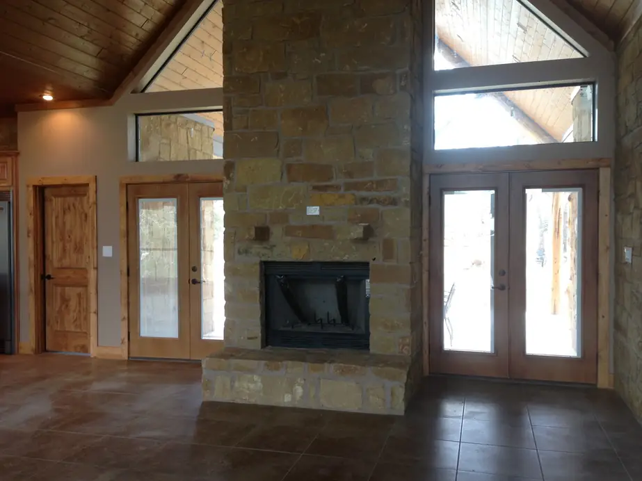 A two sided stone fireplace under a vaulted tongue and groove ceiling in an Arnold Custom Builders home