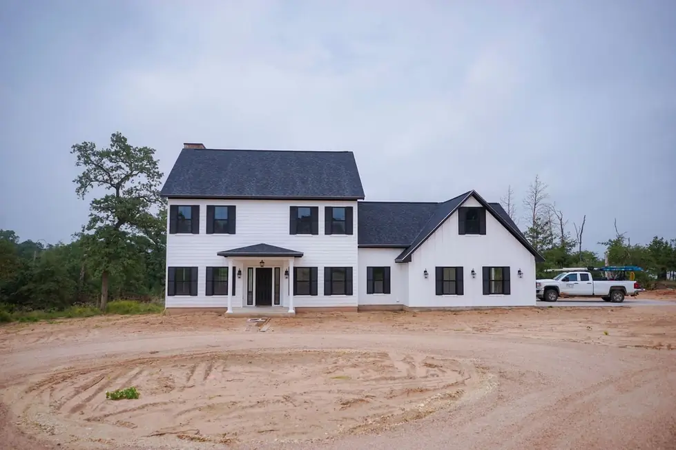 A two story white farmhouse by Arnold Custom Builders nearing completion, standing seam roof and the contractor's truck still on site