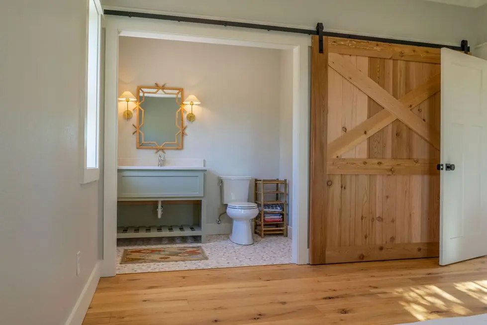A primary bathroom with a large X braced barn door and a freestanding vanity